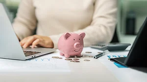Business accountant calculates income-expenses with a pink piggy bank to save money for the future. Investment concept, saving money, planning, taxes and accounting.