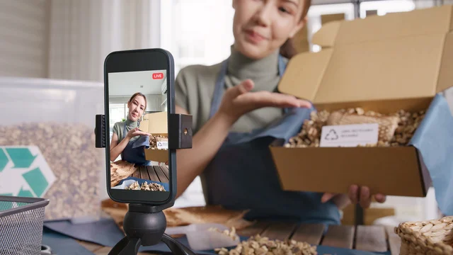 Asian young woman record video on TikTok IG reel Instagram shop happy side hustle showing off packaged product